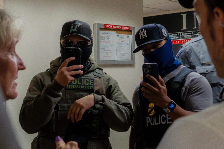 Two ICE agents film the press using smartphones in the hallway outside the immigration court at 26 Federal Plaza in New York USA on July 11 2025. The Department of Homeland Security has been acquiring new tools to identify people and monitor them.
