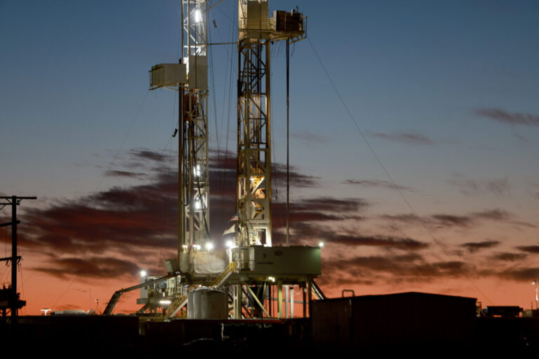 Against a blue-orange sunset, a tall oil drilling rig stands in the Permian Basin on March 13, 2022, in Midland, Texas.
