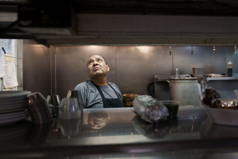 Miguel Hernandez reads an order slip while standing in a restaurant kitchen.