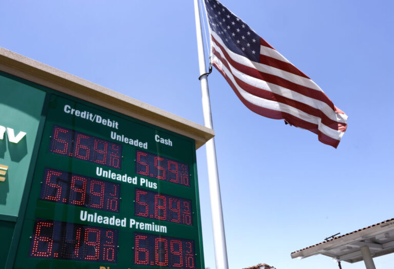 An American flag on a tall flagpole flies above a sign displaying gas prices in red digital numbers at a gas station in Arcadia, California, on May 11.