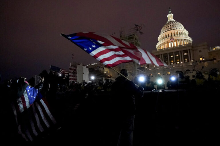 Protesters hold flags as they are pushed back by police on Jan. 6, 2021, after President Trump supporters stormed the U.S. Capitol.