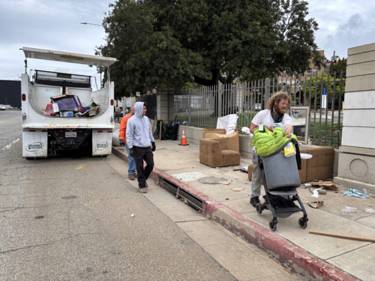 Iraq war veteran Irving Webb moves his belongings as sanitation workers clear the sidewalk, where he spent some nights in April, outside the Los Angeles VA campus.