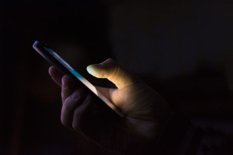 a hand holding a smart phone in the dark