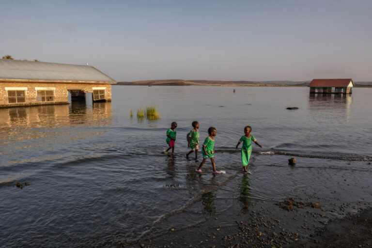 School children walk through the shallows past submerged and abandoned school buildings at the El Molo Bay primary school in Komote, Kenya. Teachers at the school say the buildings have become a breeding ground for crocodiles.