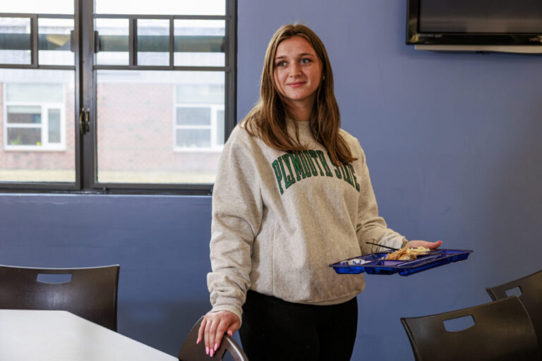 Mady Worcester stands at school, holding a cafeteria plate of fish tacos in one hand.