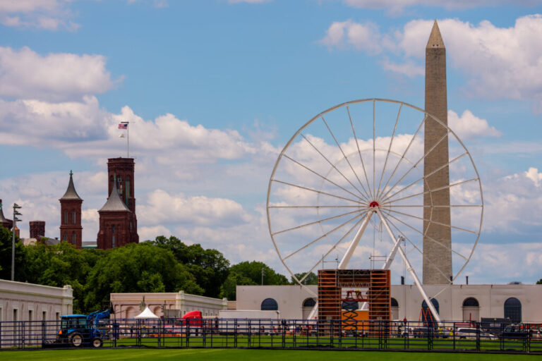 A Ferris wheel sits on the National Mall, with the Smithsonian Castle and Washington Monument in the background.