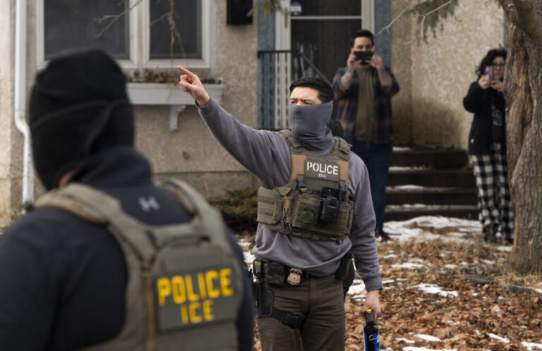 In this photo, two observers holding up smartphones stand in the background as they record two Immigration and Customs Enforcement agents in Minneapolis on February 5.