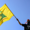 A masked demonstrator waves a flag of Hezbollah during a demonstration supporting the Palestinians in Beirut on Oct. 20, 2023.