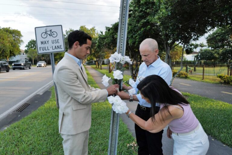 Martin Langesfeld (left), Pablo Langesfeld (center) and their mother, Andrea Langesfeld (right), wrap flowers around a street sign in Doral, Florida, on April 27, 2025. The sign dedicates the street corner in honor of their sister and daughter, Nicky, who died in the 2021 collapse of the Champlain Towers South building in Surfside, Florida.