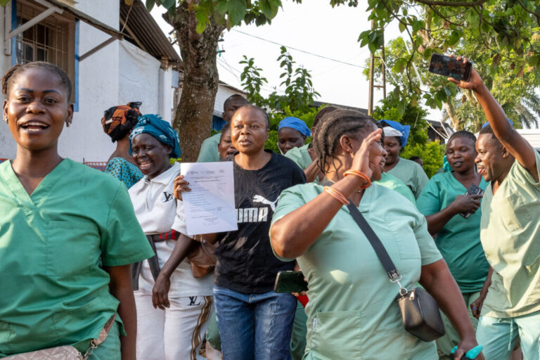 Healthcare workers celebrate the recovery and discharge of Ebola survivor Florence Mangembo at the Mongbwalu General Referral Hospital, in Mongbwalu, Ituri province, Democratic Republic of Congo, on June 16, 2026. Mangembo is standing outdoors among the healthcare workers, who are wearing green scrubs.