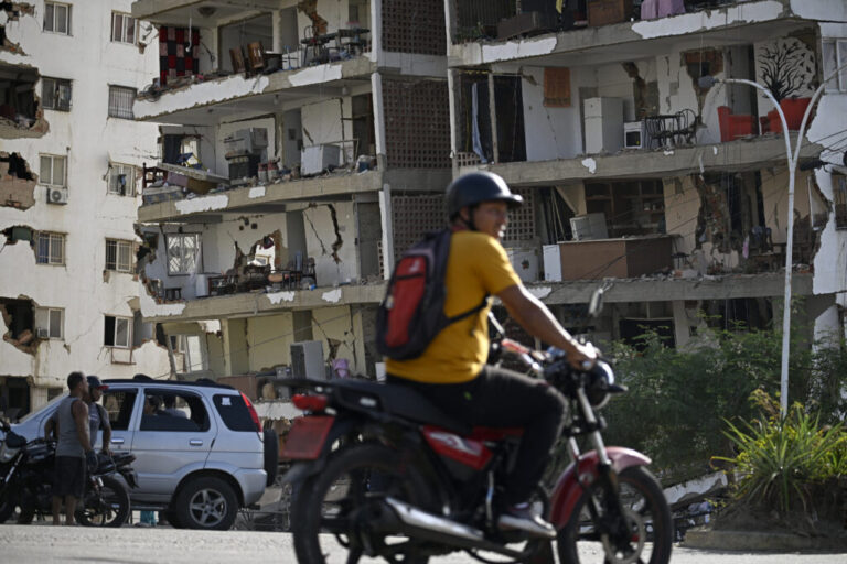 Residents look at a damaged apartment building following an earthquake in Catia La Mar, La Guaira state, about 30 km northwest of Caracas, on June 25, 2026.