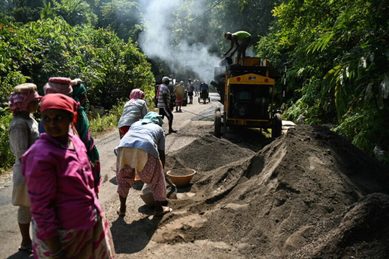 TOPSHOT - This photograph taken on March 26, 2026 shows construction workers operating a smoke-spewing tarmac mixer to build a road cutting through forest land, as part of the Great Nicobar Island Project, a government-backed mega-development undertaking on the outskirts of Campbell Bay in Great Nicobar Island. On a remote island in the Andaman Sea, bulldozers are tearing into pristine forests home to one of Earth's most isolated people -- part of India's ambition for a $9 billion megaport, airport and city. Designed to rival China's investments around the Indian Ocean, New Delhi's colossal project will be built on Great Nicobar Island, a site offering a naval presence far closer to Southeast Asia than India's mainland. (Photo by R. Satish BABU / AFP via Getty Images) / TO GO WITH 'India-Nicobar-Politics-Environment-Economy' FOCUS