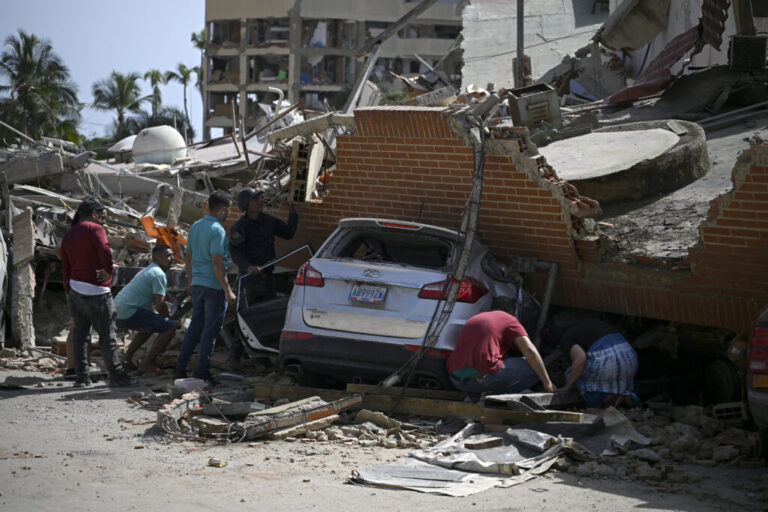People search through the rubble around a car trapped beneath the collapsed remains of a residential building following an earthquake in Catia La Mar, La Guaira state, about 30 km northwest of Caracas.