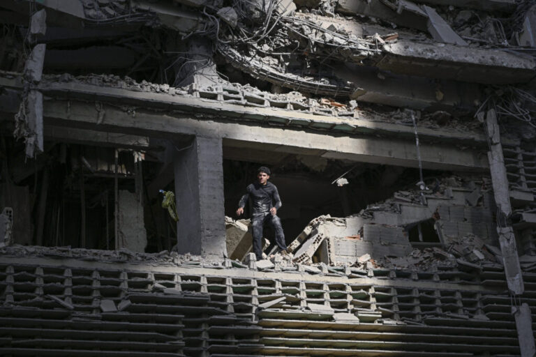 A man looks out from a damaged apartment building following an earthquake.