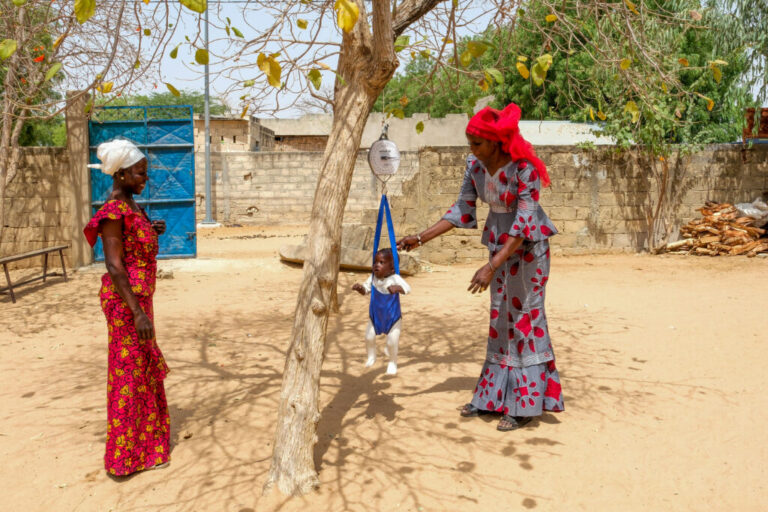 Keur Mbar, Senegal (May 4, 2026) - Adama Faye, a community healthworker, weighs Aliou Faye, the son of Ndiolle Diouf at the village's health hut.