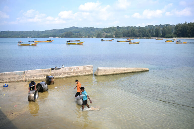 People clean vessels near Campbell Bay at Great Nicobar island on March 28, 2026. (Photo by R.Satish BABU / AFP via Getty Images)