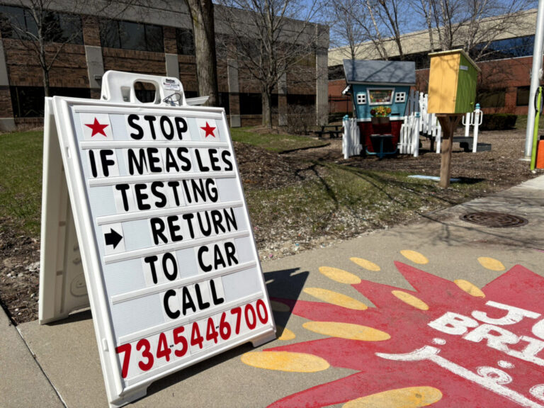 A sign on a sidewalk reads