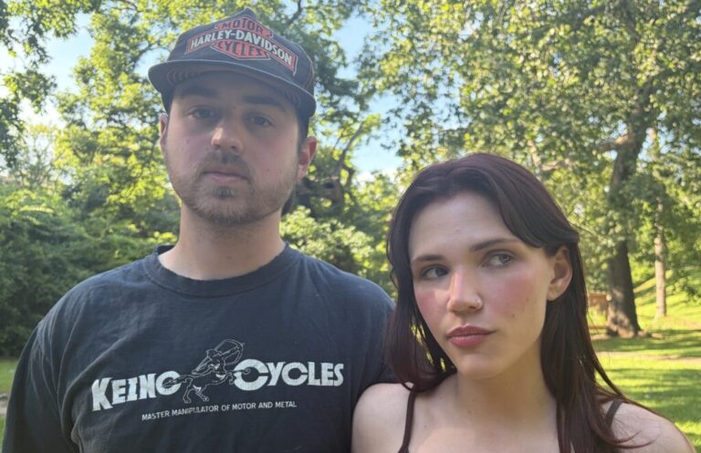 In this photo, Chloe Troub stands on the right side of the frame, and her boyfriend, Carson McDonald, is standing on the left side of the frame. Standing outdoors, they are photographed from about the shoulders up, and trees are in the background.
