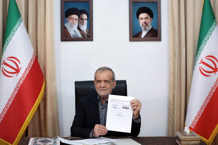 In this photo provided by the Islamic Republic News Agency (IRNA), Iranian President Masoud Pezeshkian displays a memorandum of understanding signed with U.S. President Trump aimed at ending the war and launching negotiations on a broader agreement, in Tehran, Iran, early Thursday.