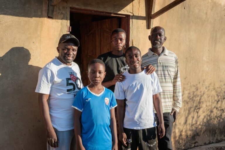 The boys pose for a picture with Pastor Billy (left) and their Uncle John (right) outside their home.