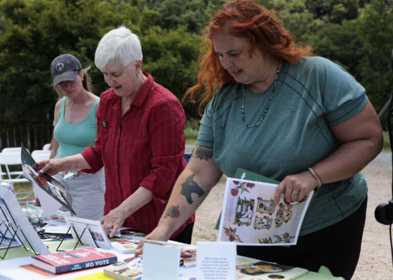 Zinn Education Project’s Deborah Menkart, in red shirt, shares examples of banned books and other reading materials during the America 433 pop-up event at Harpers Ferry National Historical Park on June 19.