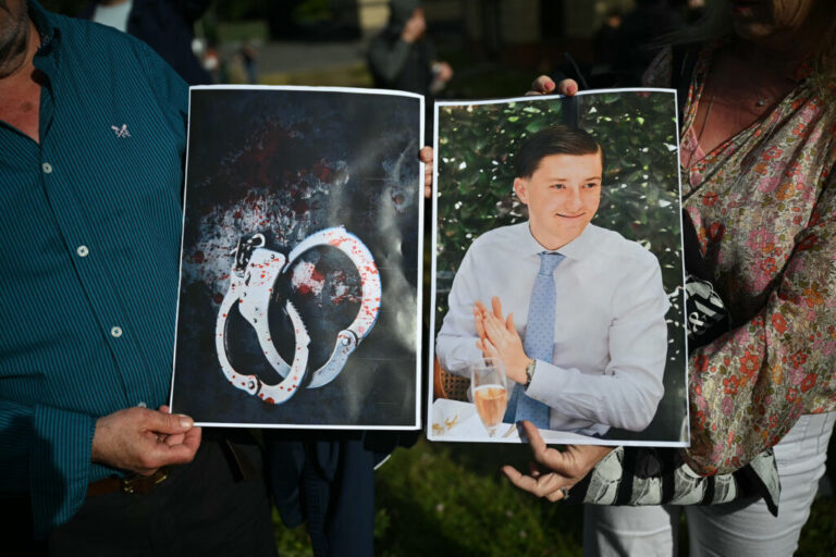 People hold images of victim Henry Nowak and blood-covered handcuffs as they take part in a protest outside of Southampton Central Police Station in Southampton, southern England, on Tuesday, following the murder of Nowak by Vickrum Digwa in December 2025.