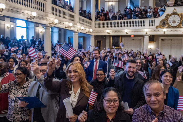 New U.S. citizens, holding up American flags and standing in rows, take part in a naturalization ceremony at Faneuil Hall in Boston on January 8.