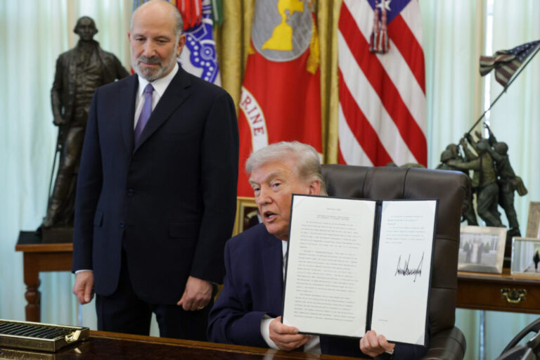 President Trump holds up an executive order to limit mail-in voting as Commerce Secretary Howard Lutnick looks on in the White House’s Oval Office in March.