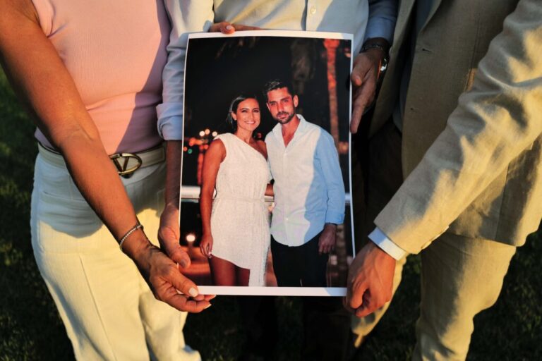 Andrea Langesfeld (left), Pablo Langesfeld (center) and Martin Langesfeld (right) hold a photo of their daughter and sister Nicky Langesfeld and her husband, Luis Sadovnic, on April 27, 2026. The couple died in the 2021 collapse of the Champlain Towers South condominium building in Surfside, Florida.