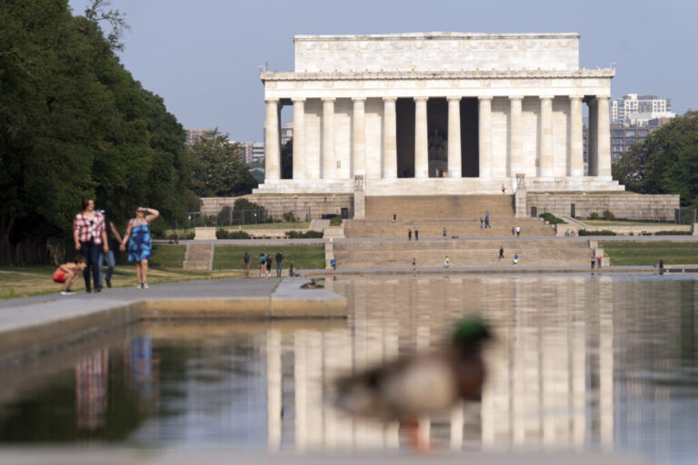 With a blue sky above the Lincoln Memorial, people walk along the reflection pool in Washington, D.C., on June 9, 2023.
