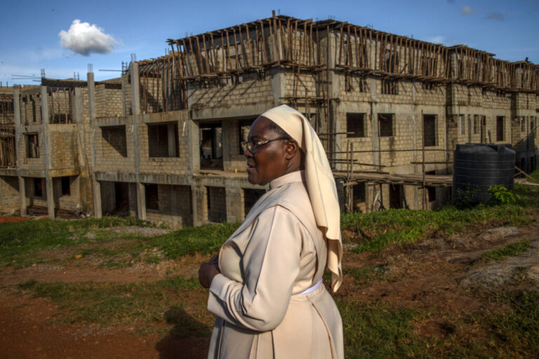 Sister Jean Francis stands outside the Little Sisters of St. Francis premises in Nkokonjeru, Uganda, on May 11, 2026, in front of a newly constructed building intended to support the congregation’s growing needs, including care for retired sisters. After more than 25 years working in healthcare, Sister Jean Francis helped advocate for a partnership between the Little Sisters of St. Francis and the African Palliative Care Association to improve end-of-life care for aging nuns in Uganda. The pilot program seeks to address the lack of support many retired sisters face after decades spent serving communities through schools, clinics, and religious work.