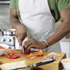 Close up of man in his 20s cutting bell peppers at home in the kitchen and engaging in meal prep.