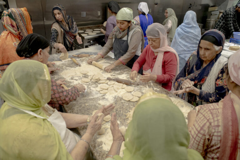 Women gather in the Gurdwara kitchen, working together to make roti for the langar, the community meal served to all visitors. Women who do not wear turbans cover their heads, in keeping with Sikh tradition that hair be covered on Gurdwara premises. Preparing langar has long been a central practice in Sikhism, dating back to Guru Nanak in the 15th century, emphasizing equality, service, and community. In Ohio, these women continue that tradition, sharing labor and food across generations, building bonds among families, newcomers, and elders, and ensuring that the Gurdwara remains a space of faith, culture, and togetherness.