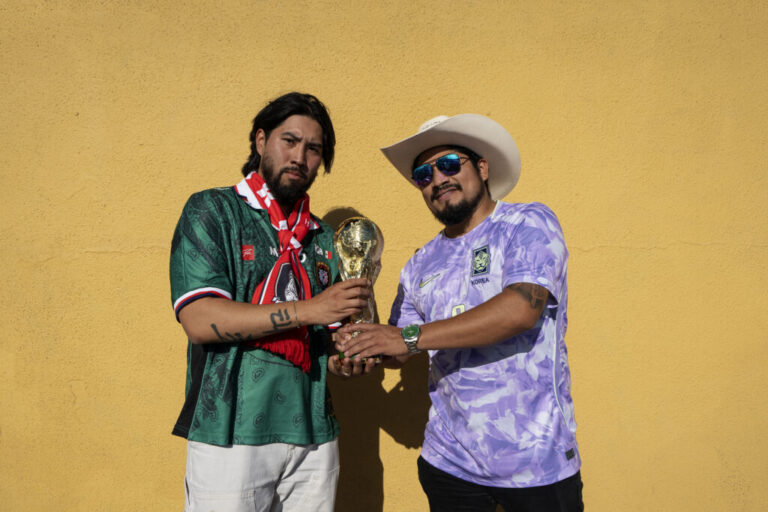 Josh Lee and Fernando Delgado pose for a portrait in Koreatown outside the Biergarten before the South Korea vs Czech Republic World Cup game with a fake trophy on June 11, 2026.