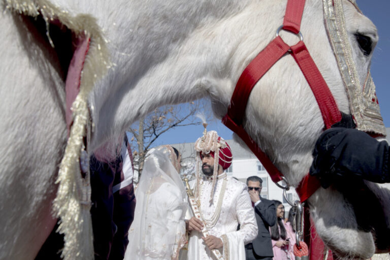 The groom, Rupinder Gill, talks with his sister before mounting his horse to head to the wedding venue. This procession, known as the Baraat, is a central part of traditional Sikh weddings, symbolizing the groom’s journey to the bride’s home or venue accompanied by family, friends, music, and dancing. In the cultural setting, the Baraat represents joy, celebration, and the community’s support for the couple.