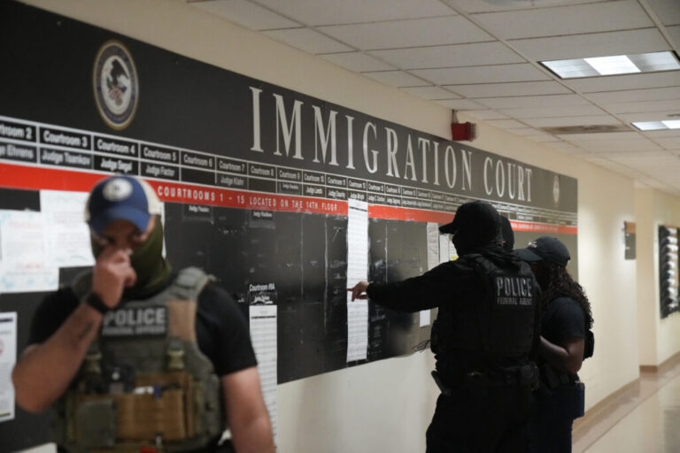 U.S. Immigration and Customs Enforcement agents look over lists of names and their hearing times and locations inside the Federal Plaza courthouse in June 2025 in New York.