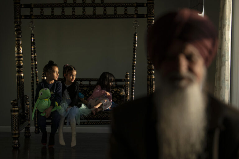 Agam Singh, 7, plays with Kermit the Frog alongside his cousins as his grandfather rests on the couch at their home in Twinsburg, Ohio. Agam’s father moved to the United States several years ago seeking better opportunities, raising his children in a space where two worlds meet—American life outside the home and Sikh values within it.  The moment reflects the continuity between generations and quite shifts within the community where elders who built the foundations of faith and culture gradually receding, while the next generation grows in a space shaped by both Sikh values and American life. Through play, imagination, and family connections, these children navigate dual identities, embracing their heritage while engaging with the world around them, balancing tradition and modernity in a uniquely American Sikh experience.