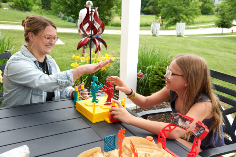Amber and Piper, 12, play with plastic robots together on a patio.