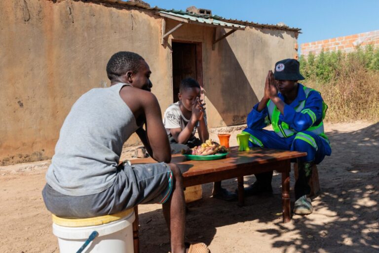 Brothers Joseph, Alumbwe and Gift pray before sharing a meal.