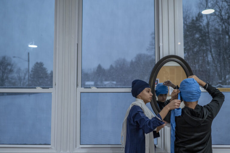 Sukhman Kaur helps Harsaajan Singh with his turban during a turban-tying class.