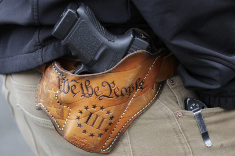 An attendee at a gun rights rally open-carries his gun in a holster that reads