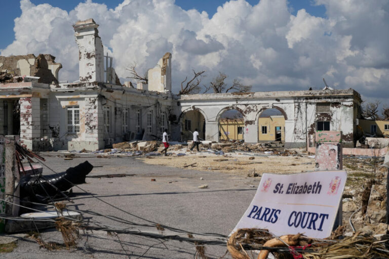 People walk past damage from Hurricane Melissa in Black River, Jamaica on Thursday, Oct. 30, 2025.