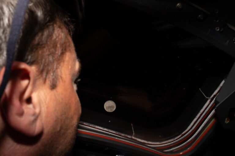 Astronaut Reid Wiseman looks out one of the Orion spacecraft's windows at the moon ahead of the crew's lunar flyby.