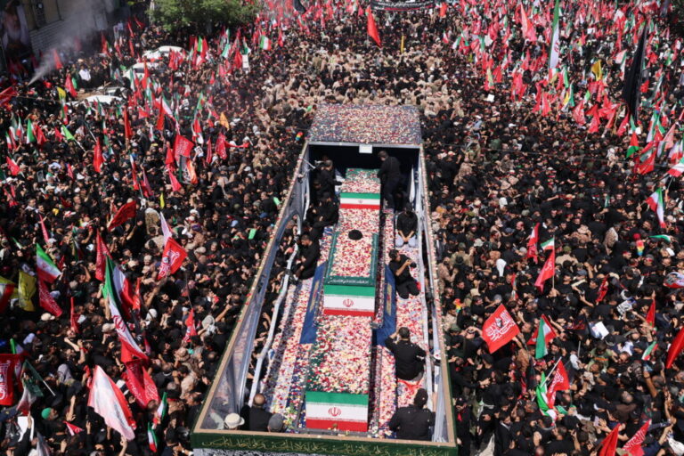 Flower petals are thrown on the coffins of Iran's slain Supreme Leader Ali Khamenei and his family members along a street during their funeral procession in Tehran on Monday.