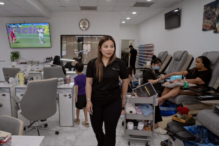 Vy Nguyen walks through while painting nails at her salon, Vina Nails, in Houston, Texas, on June 26, 2026.