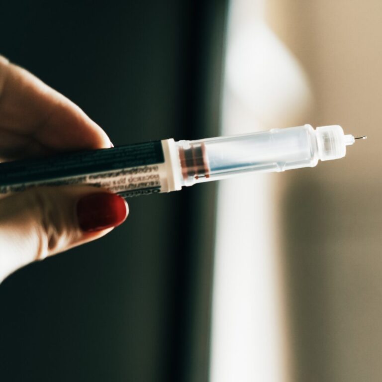 A hand holds a syringe.