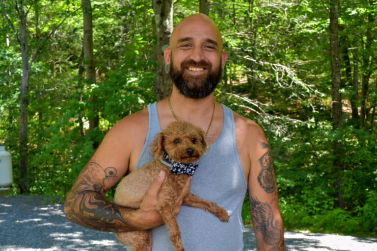 Jareed Freeman holds his dog while standing near the Deerfield River in Charlemont, Mass. on June 27, 2026.