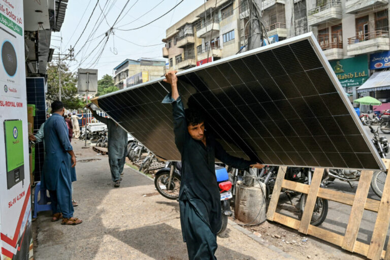 A labourer walks through Karachi with a solar panel