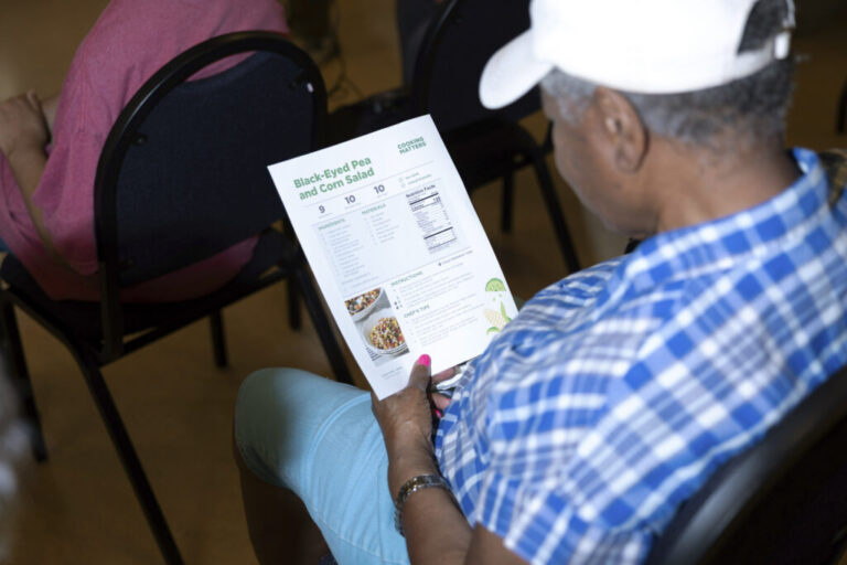 A community member reads a recipe for black-eyed pea and corn salad at a healthy cooking demonstration lead by The Food Trust at Spectrum Health in Philadelphia.