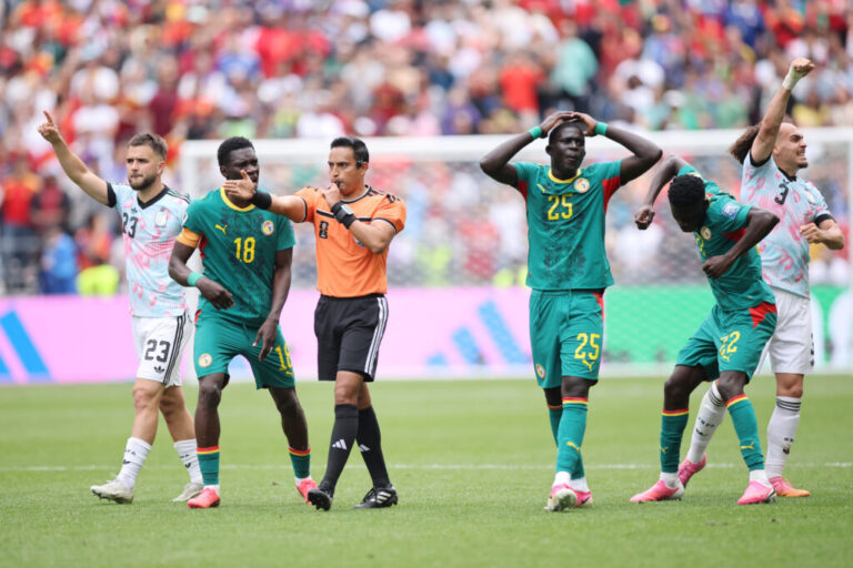Some players celebrate, and another clutches his head, as players react to FIFA referee Said Martinez when a penalty kick is awarded to Belgium after the VAR review.